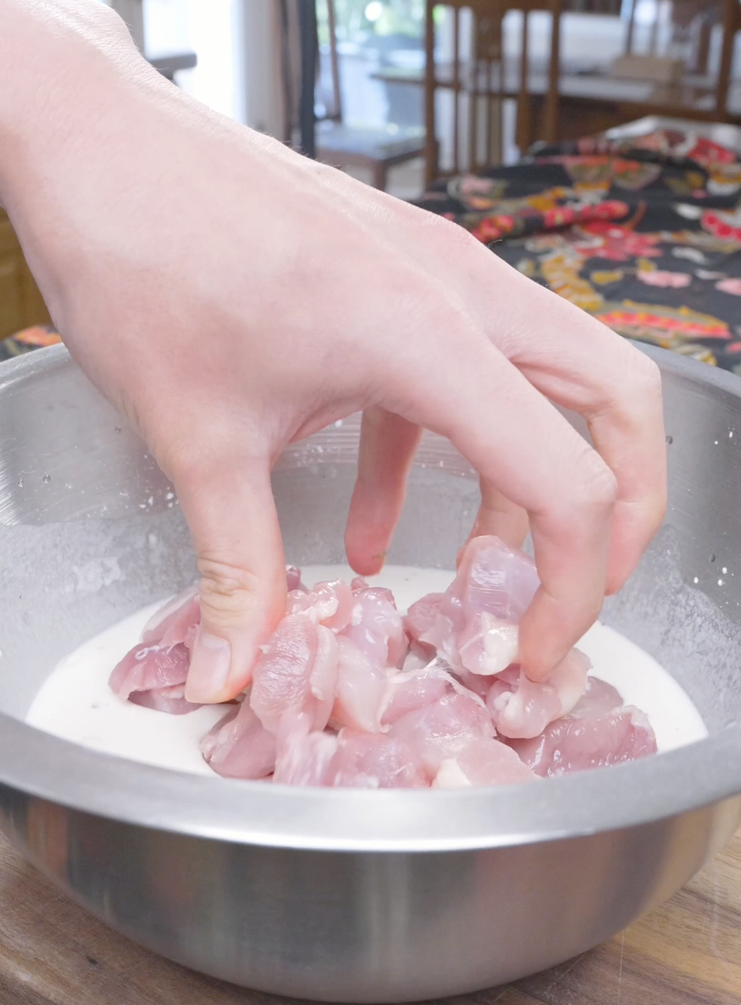 Cubed raw chicken thighs being dropped into the wet batter for Korean Popcorn Chicken Recipe.