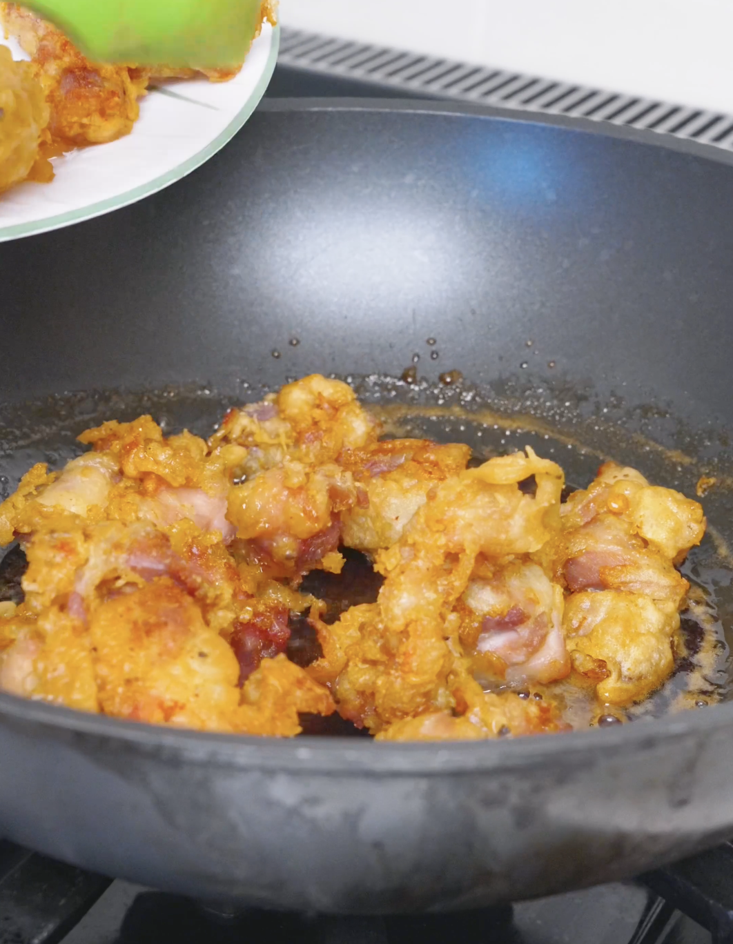 Golden fried chicken being tipped into the simmering honey glaze for Sweet Honey Fried Chicken Recipe.