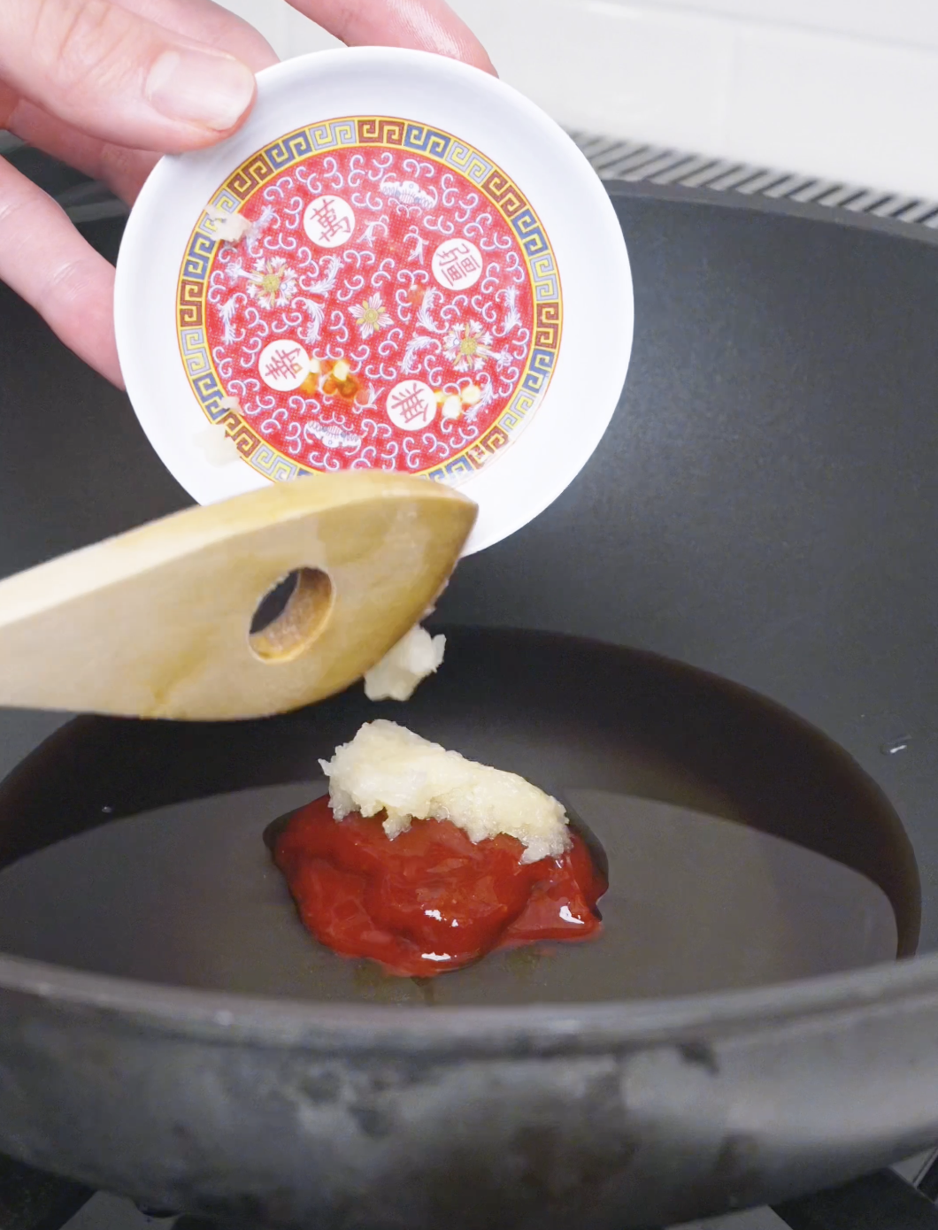 Minced garlic being added over gochujang in the pan for Korean Popcorn Chicken Recipe.