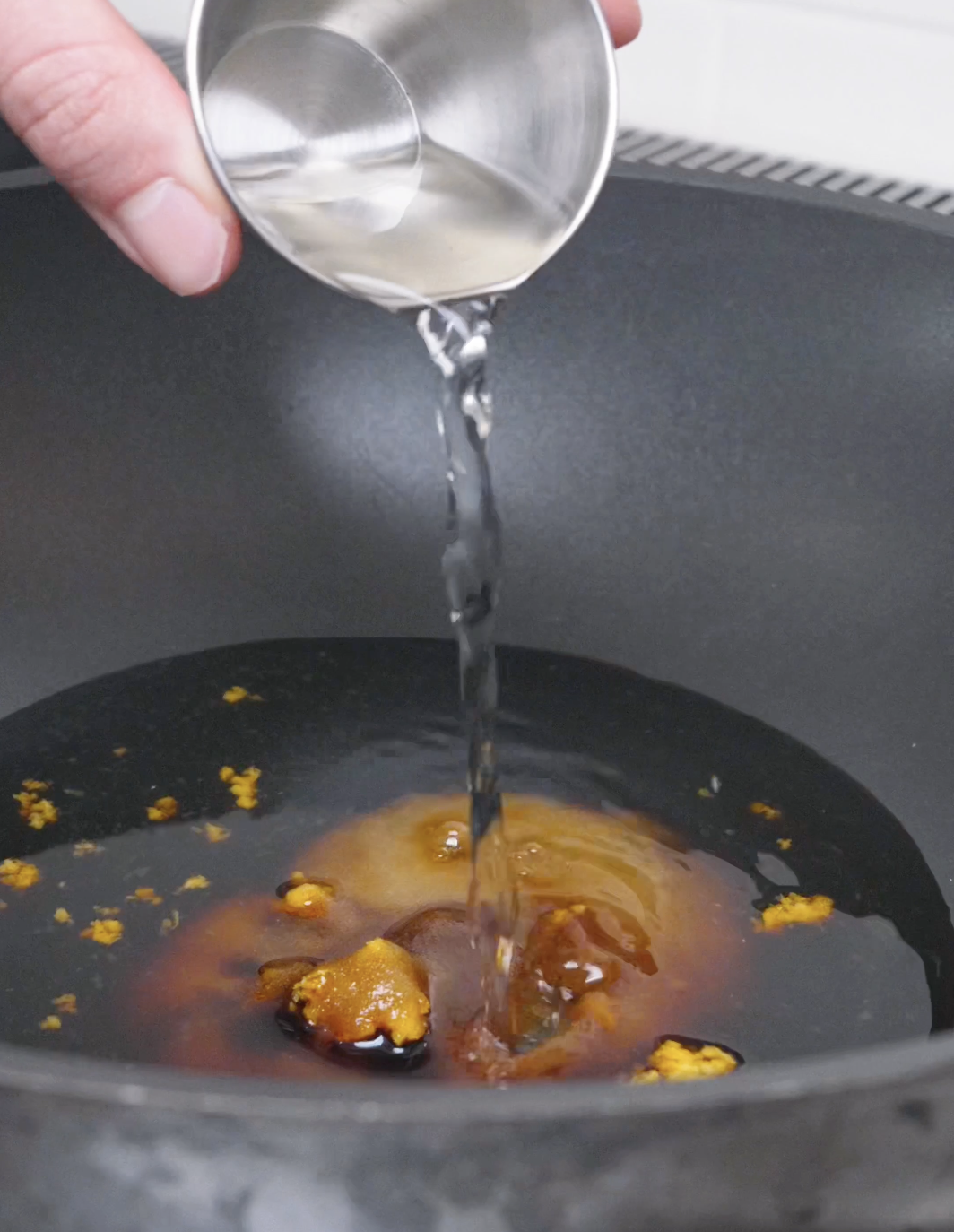 Orange juice being poured into soy sauce, sugar, garlic, and ginger for Orange Beef Recipe.