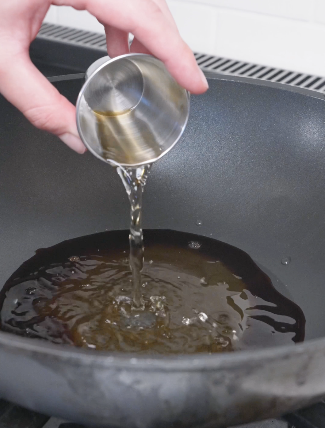 Rice vinegar being poured into the honey and soy sauce in the pan for Sweet Honey Fried Chicken Recipe.