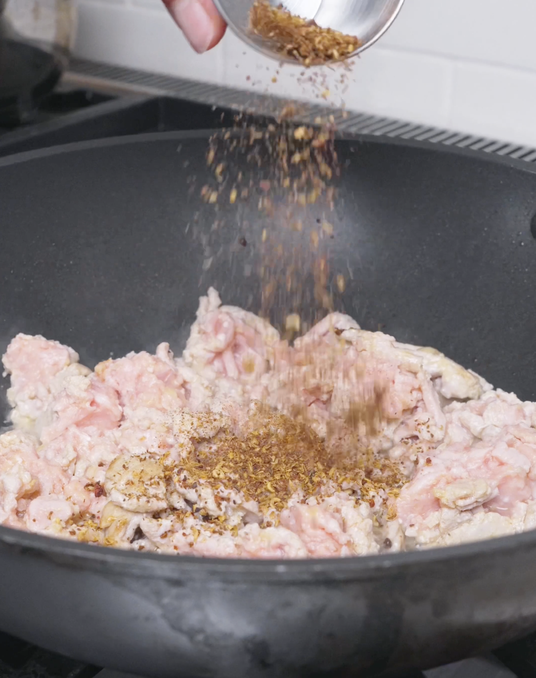 Ground Sichuan pepper being showered over the browning pork for Mapo Tofu Recipe.