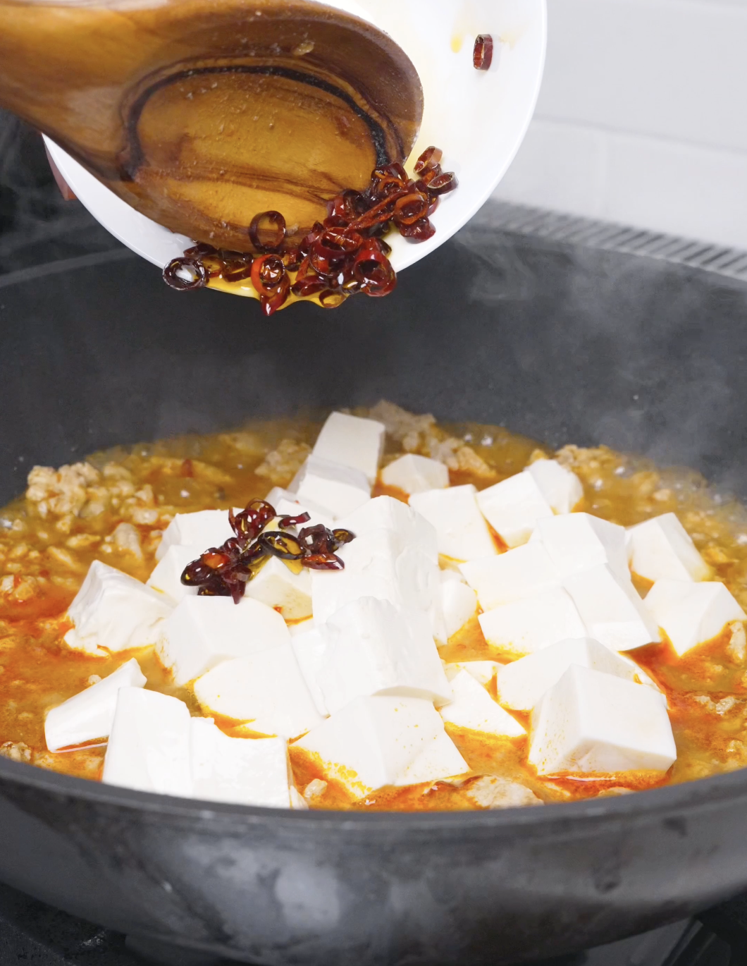 The reserved toasted chilies being returned to the pan of tofu for Mapo Tofu Recipe.