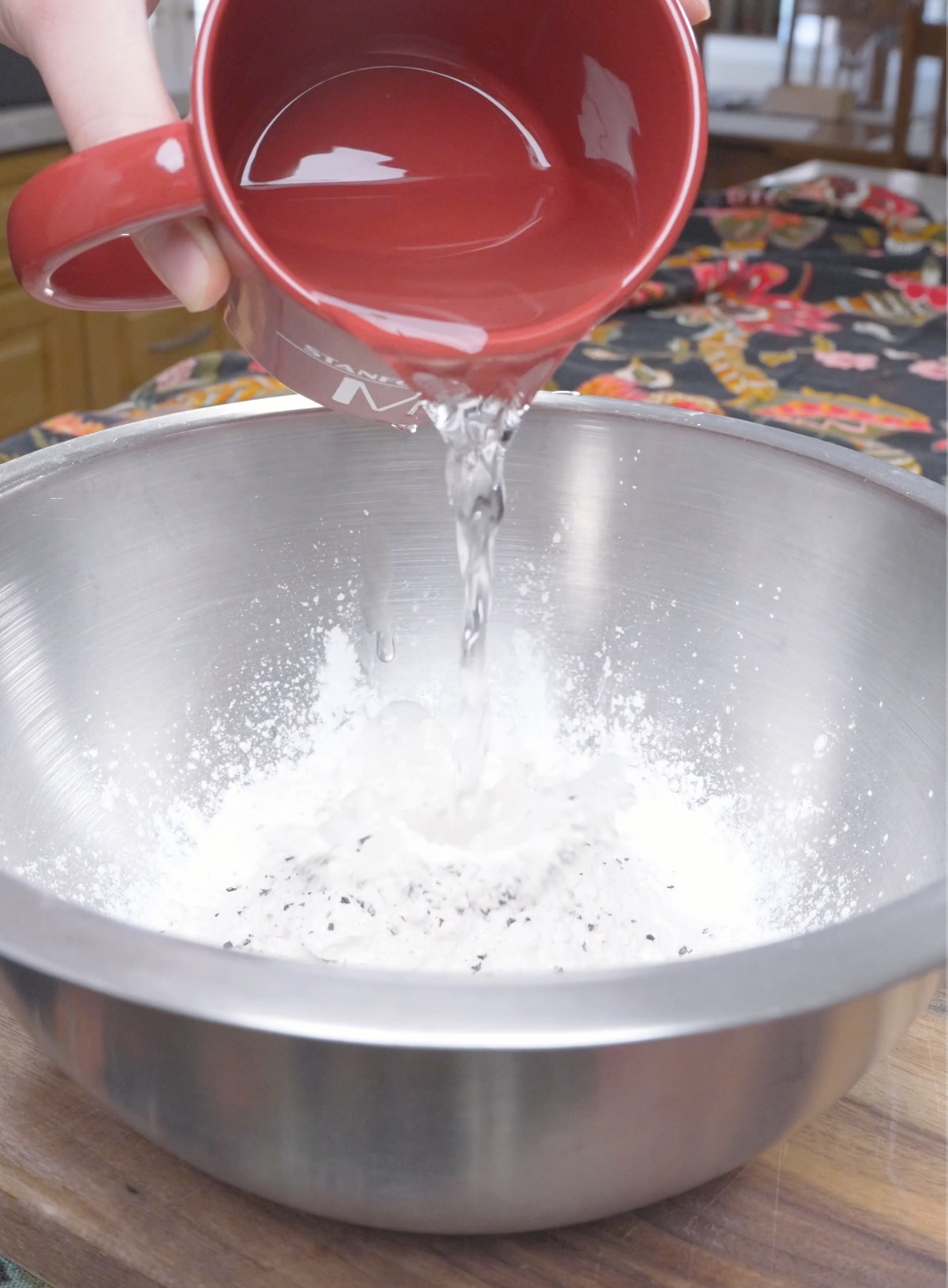 Water being poured into potato starch, flour, salt, and pepper for Korean Popcorn Chicken Recipe.