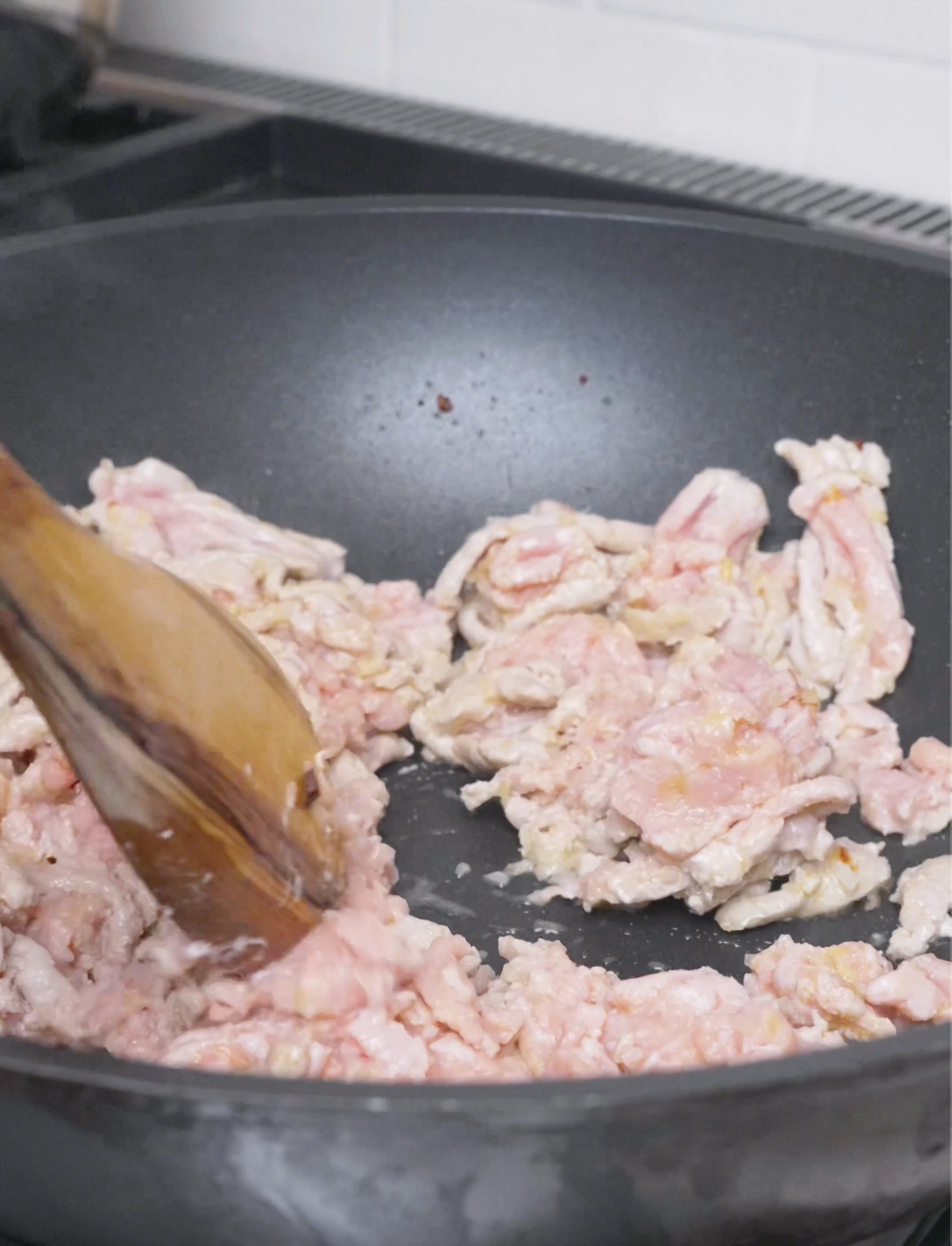 Ground pork being broken up with a wooden spoon in the wok for Mapo Tofu Recipe.