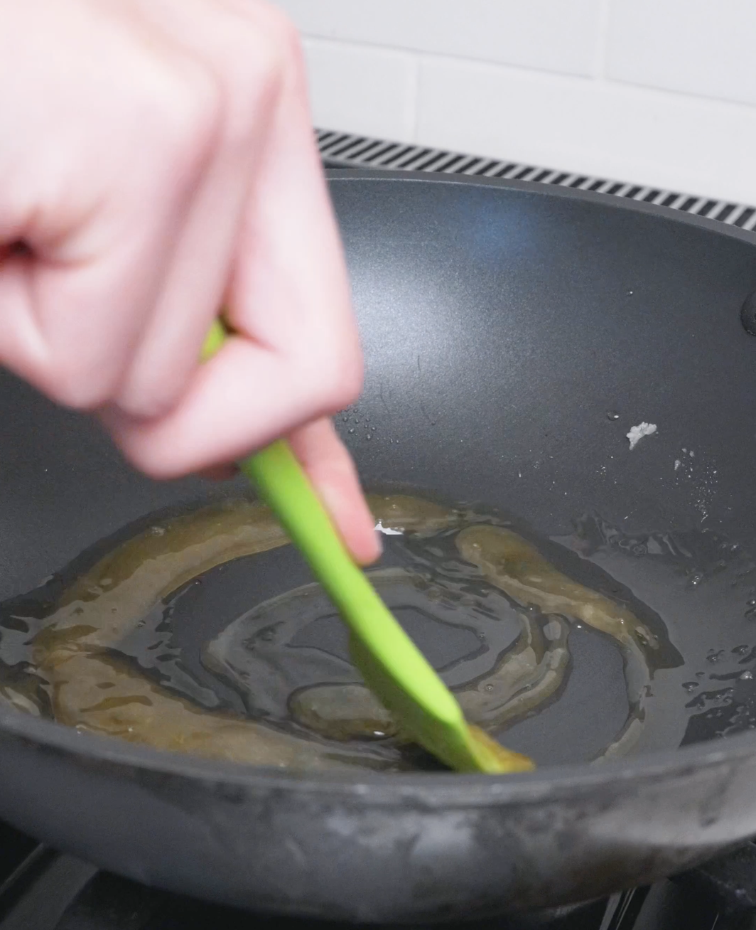 The sugar melting into a golden-brown liquid caramel in the pan for Red Braised Pork Belly Recipe.