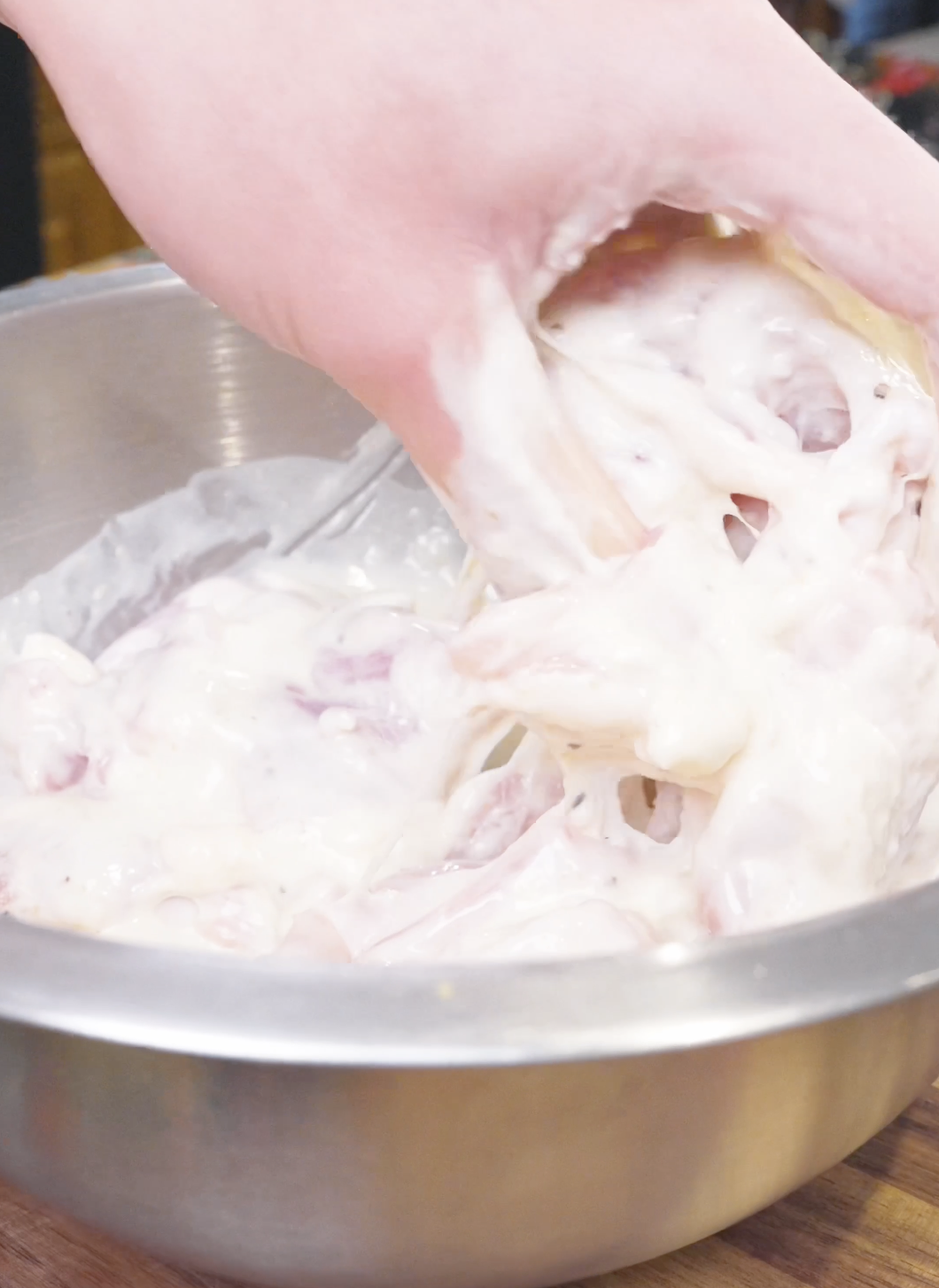Chicken being turned by hand until every piece is coated in batter for Sweet Honey Fried Chicken Recipe.