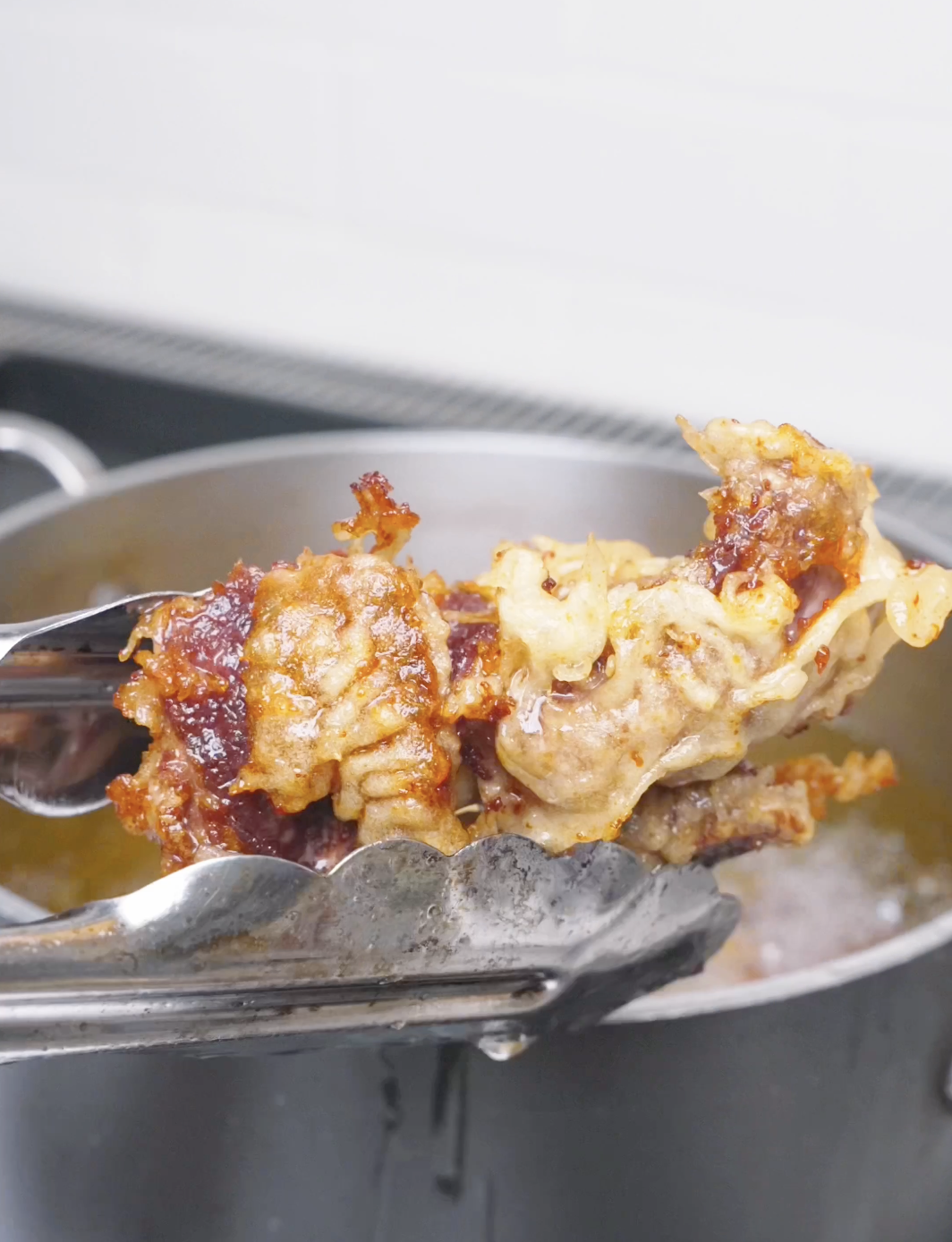 Golden, crisp-edged fried beef being lifted from the oil to rest for Orange Beef Recipe.