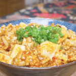 Finished Mapo Tofu Recipe in a blue bowl with silken tofu in red sauce and scallions.
