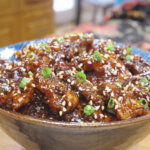 Finished Orange Beef Recipe in a bowl with crispy glazed beef, sesame seeds, and scallions.
