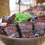 Finished Red Braised Pork Belly Recipe in a bowl with deep mahogany glazed chunks and scallions.