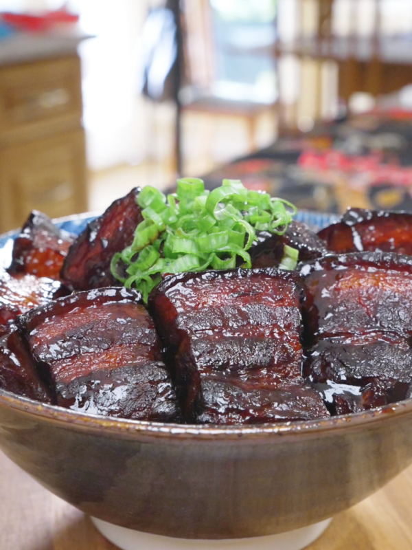 Finished Red Braised Pork Belly Recipe in a bowl with deep mahogany glazed chunks and scallions.