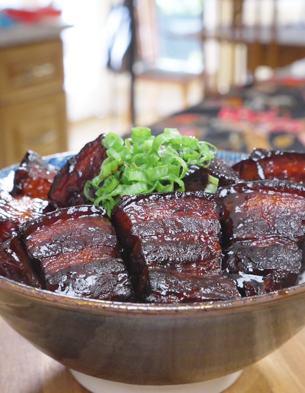 Finished Red Braised Pork Belly Recipe in a bowl with deep mahogany glazed chunks and scallions.