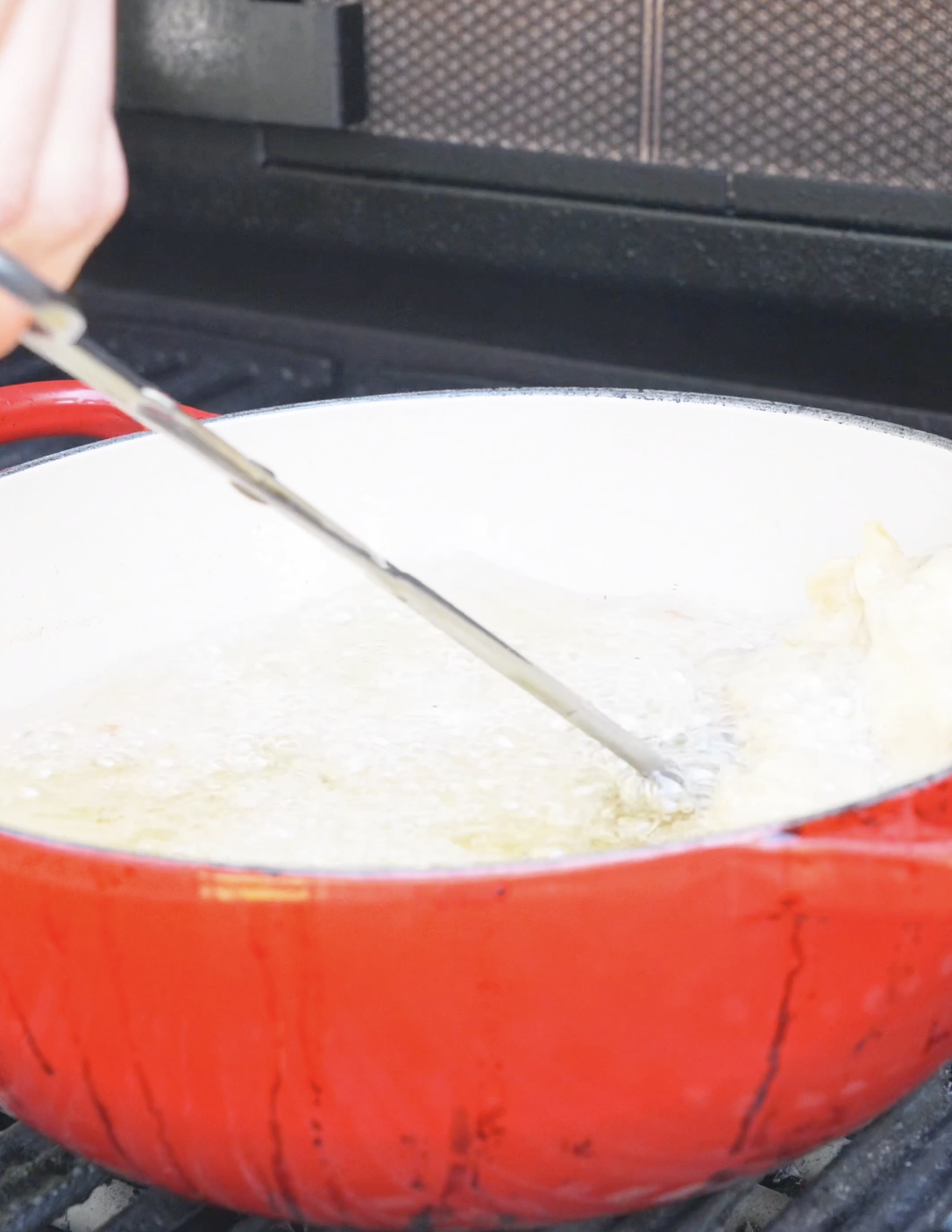 Battered chicken frying in a red dutch oven full of bubbling oil for Sweet Honey Fried Chicken Recipe.