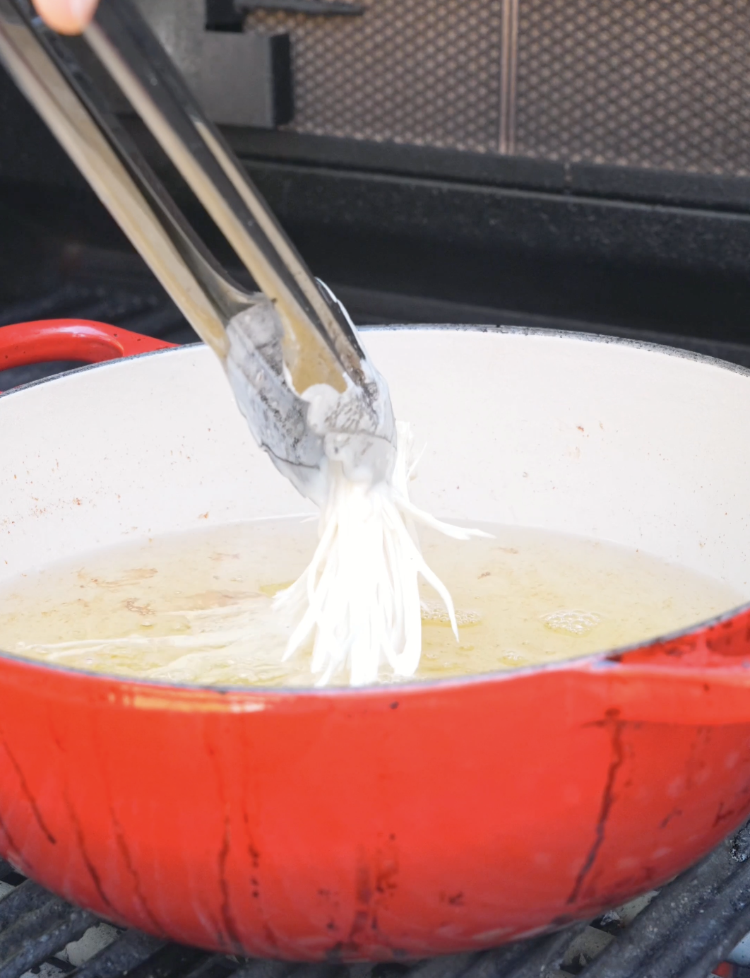 Battered enoki clusters bubbling in hot oil while making Crispy Fried Enoki Mushrooms Recipe.