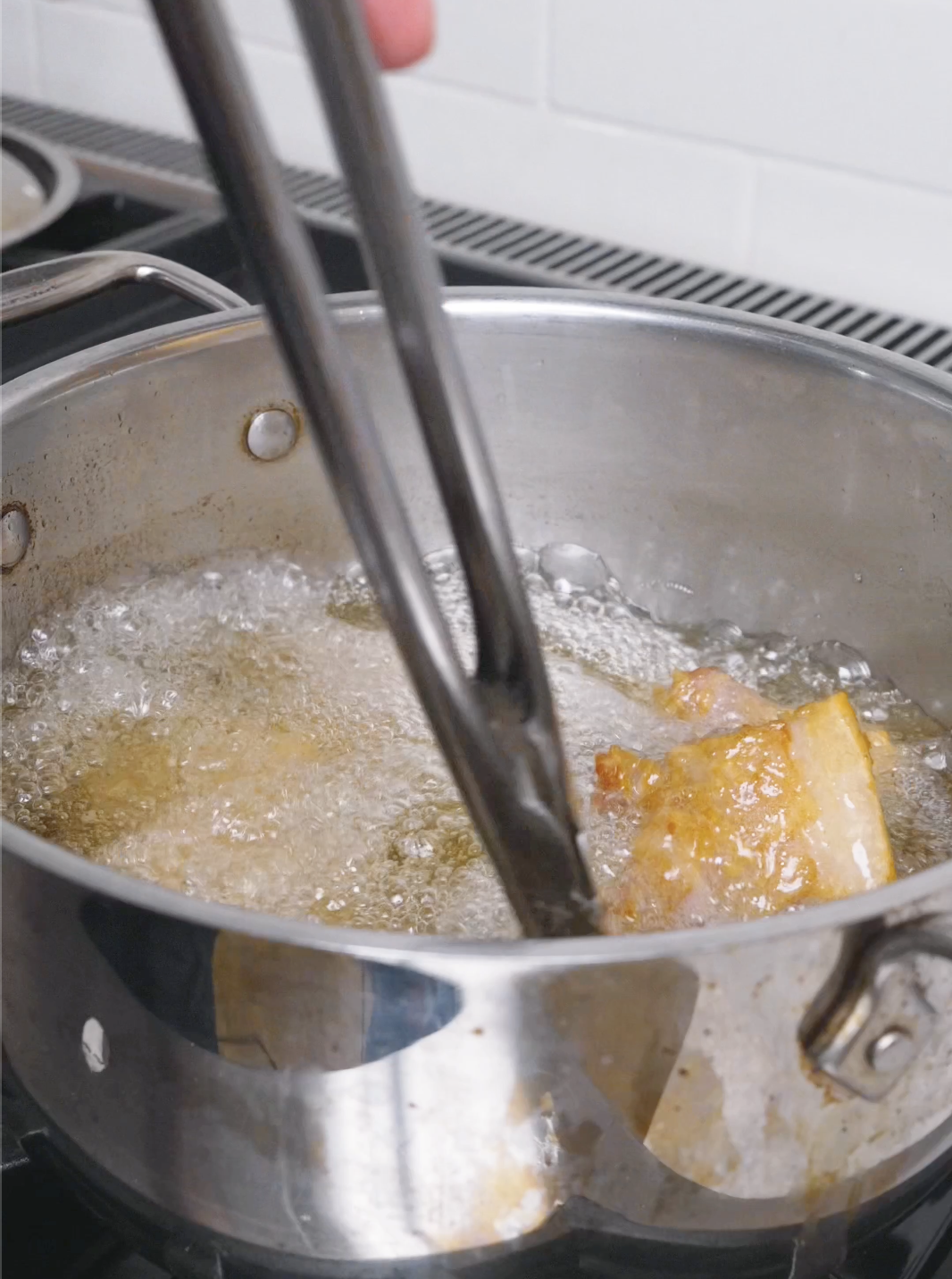 Coated pork belly cubes bubbling away in a pot of hot oil for Deep Fried Pork Belly Recipe.