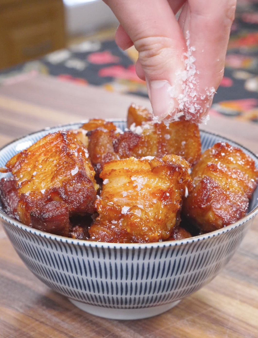 Flaky salt being sprinkled over the bowl of Deep Fried Pork Belly Recipe.