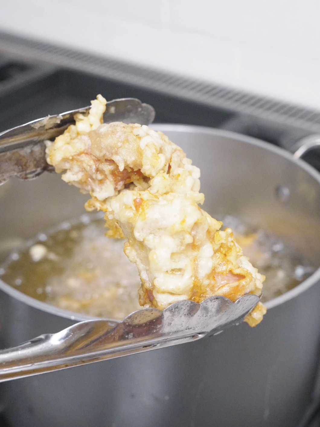Craggy golden fried chicken being lifted out of the oil for Korean Popcorn Chicken Recipe.