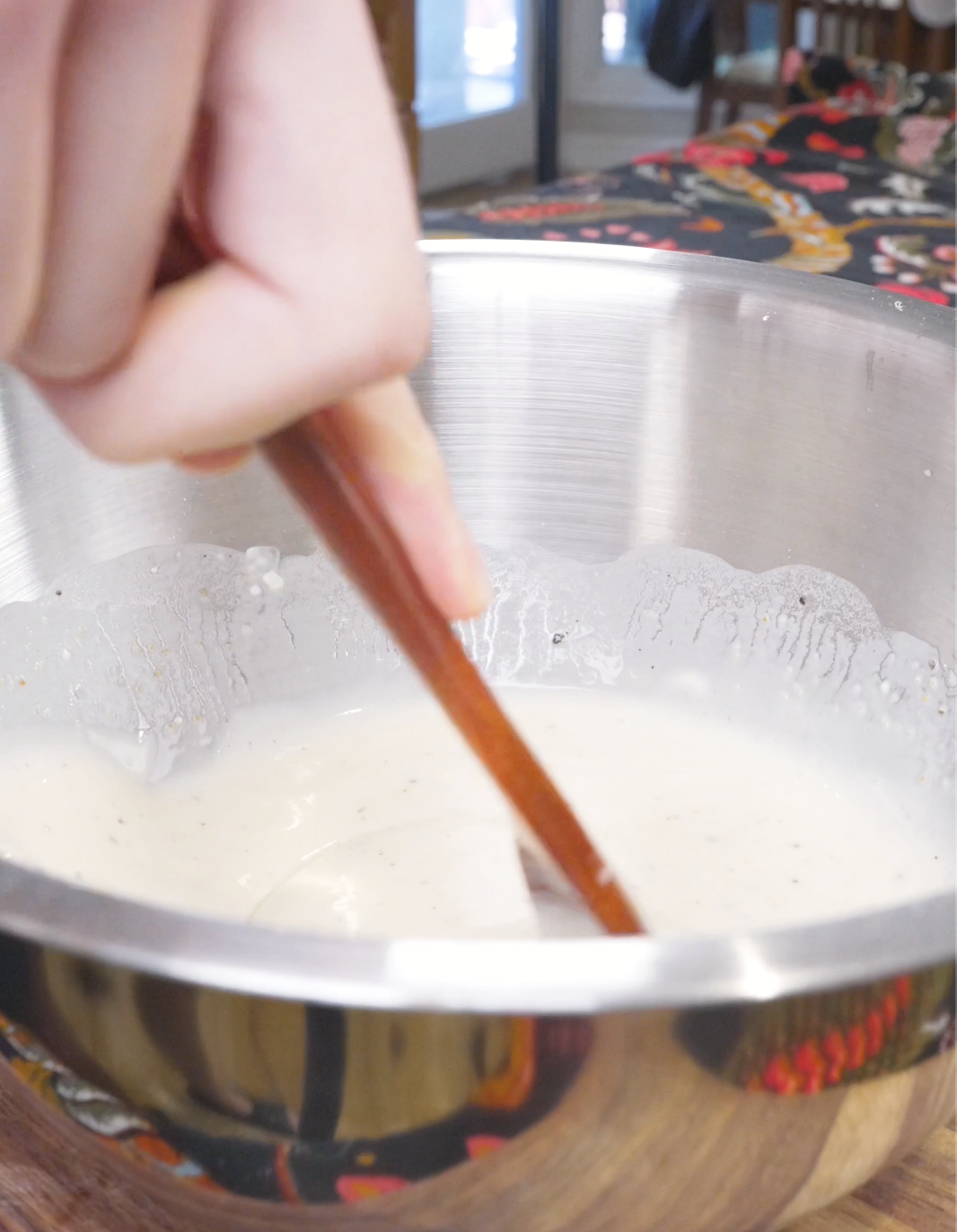 Water being whisked into the dry ingredients to form a smooth batter for Crispy Fried Enoki Mushrooms Recipe.