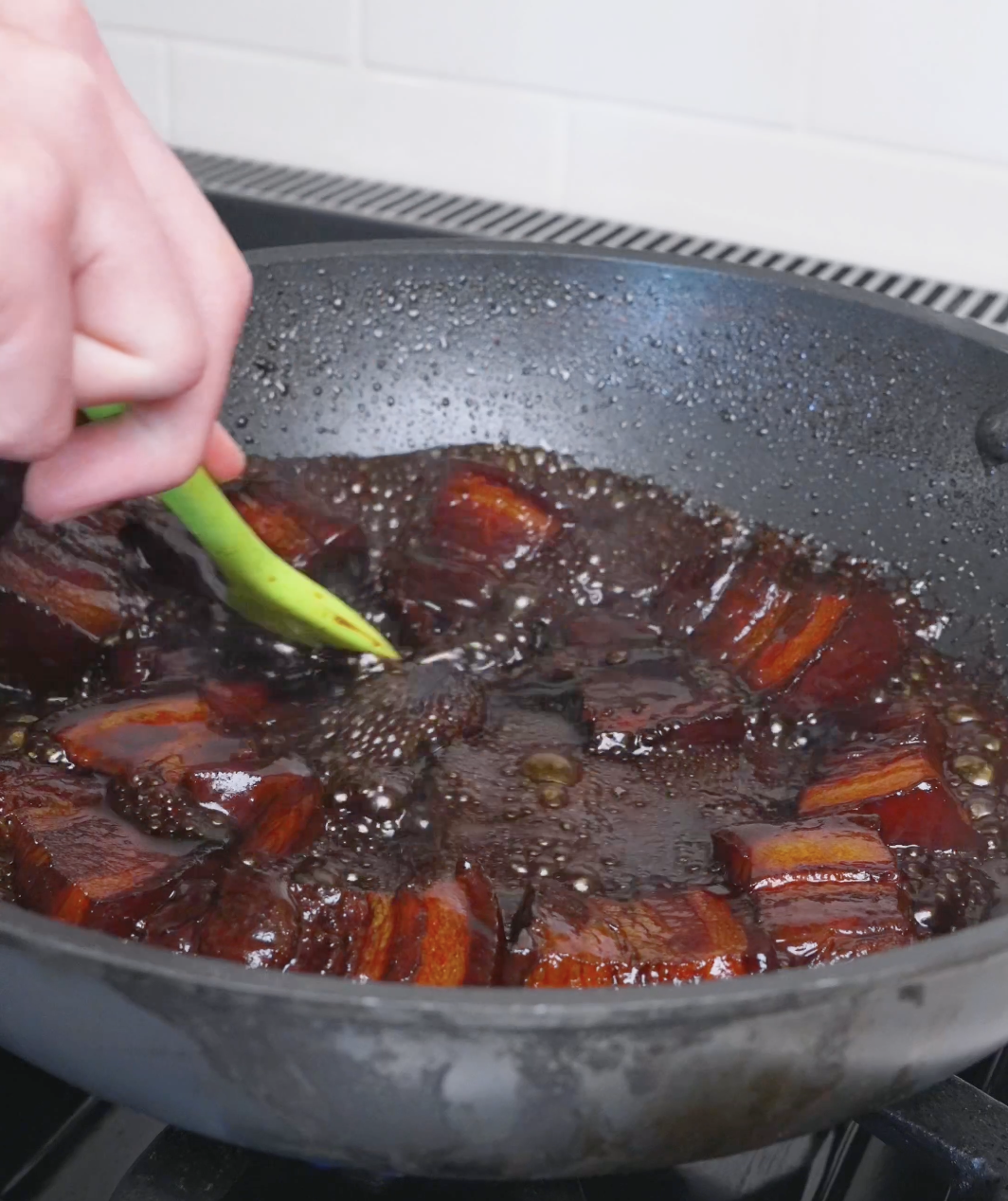 The braising liquid bubbling down into a dark, thick glaze for Red Braised Pork Belly Recipe.