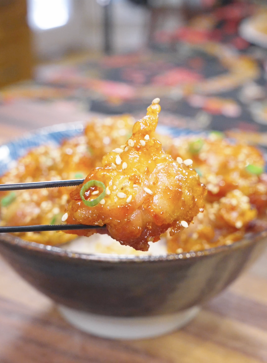 Chopsticks lifting a crunchy, honey-glazed piece above the bowl of Sweet Honey Fried Chicken Recipe.