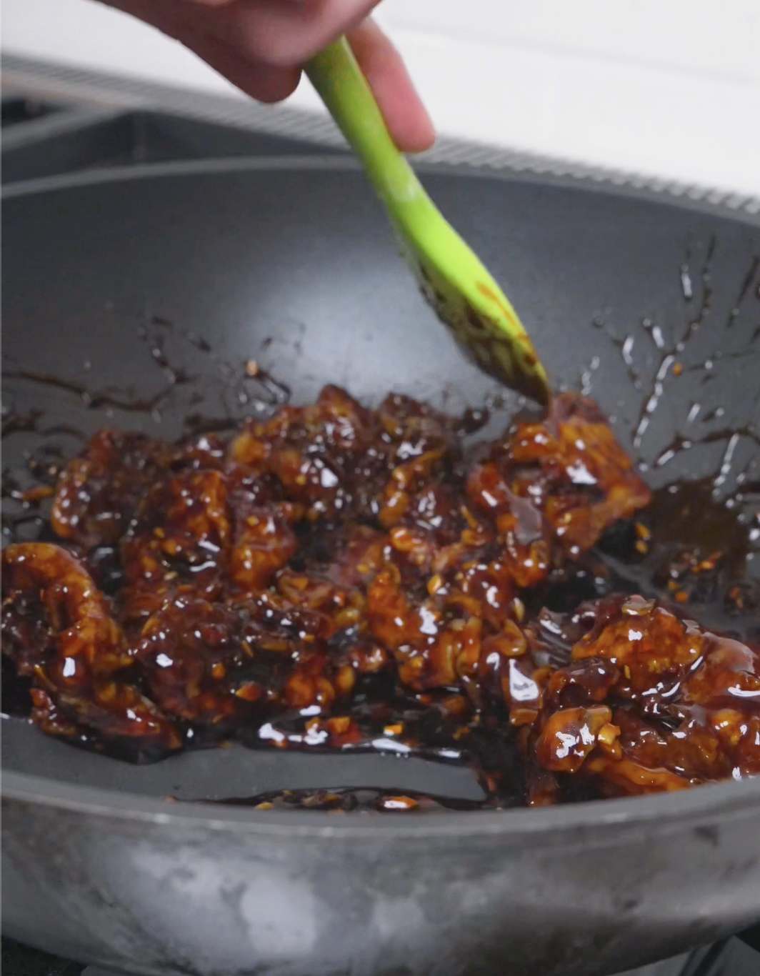 Beef being tossed until the glossy orange glaze coats every piece for Orange Beef Recipe.